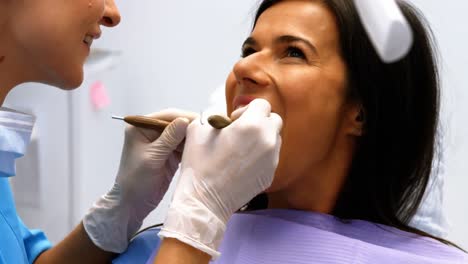 Dentist-examining-a-female-patient-with-tools