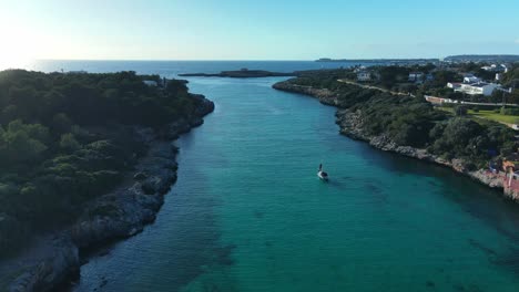 Strand-Von-Sa-Caleta-Auf-Menorca,-Spanien,-Gesehen-Bei-Sonnenuntergang-Mit-Einer-Luxusyacht,-Die-Beobachtet,-Wie-Die-Sonne-Unter-Dem-Horizont-Versinkt