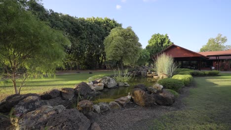 wide pull back of a pond with a red house in the background