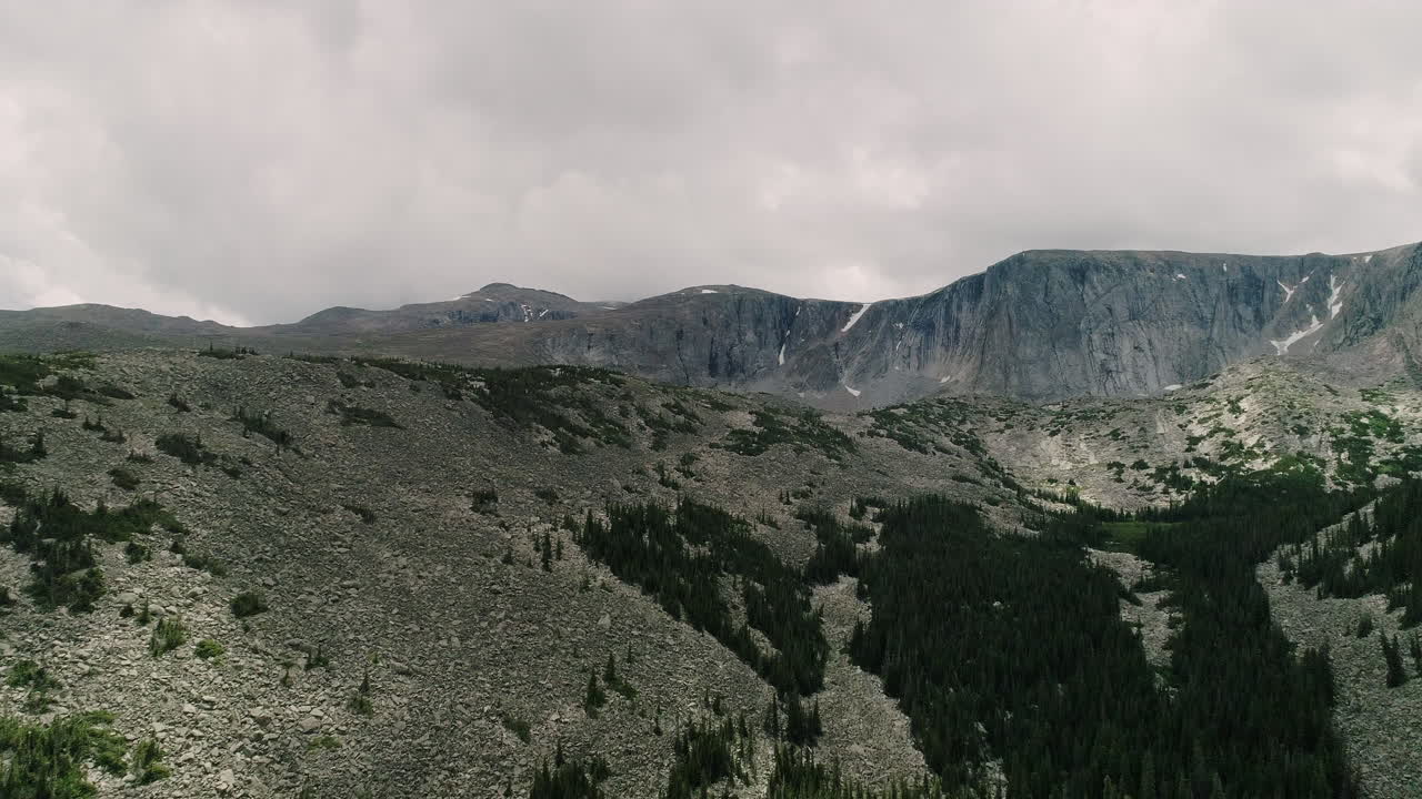 antena del lago en la cuenca de montañas cubiertas de pinos y en la distancia picos nevados