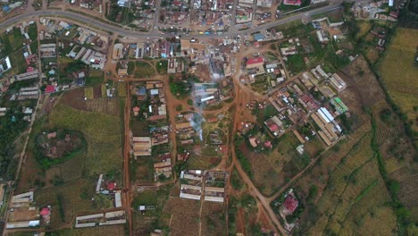 Aerial-view-of-pile-of-trash-burning-on-a-house-yard-in-rural-Africa---high-angle,-reverse,-drone-shot