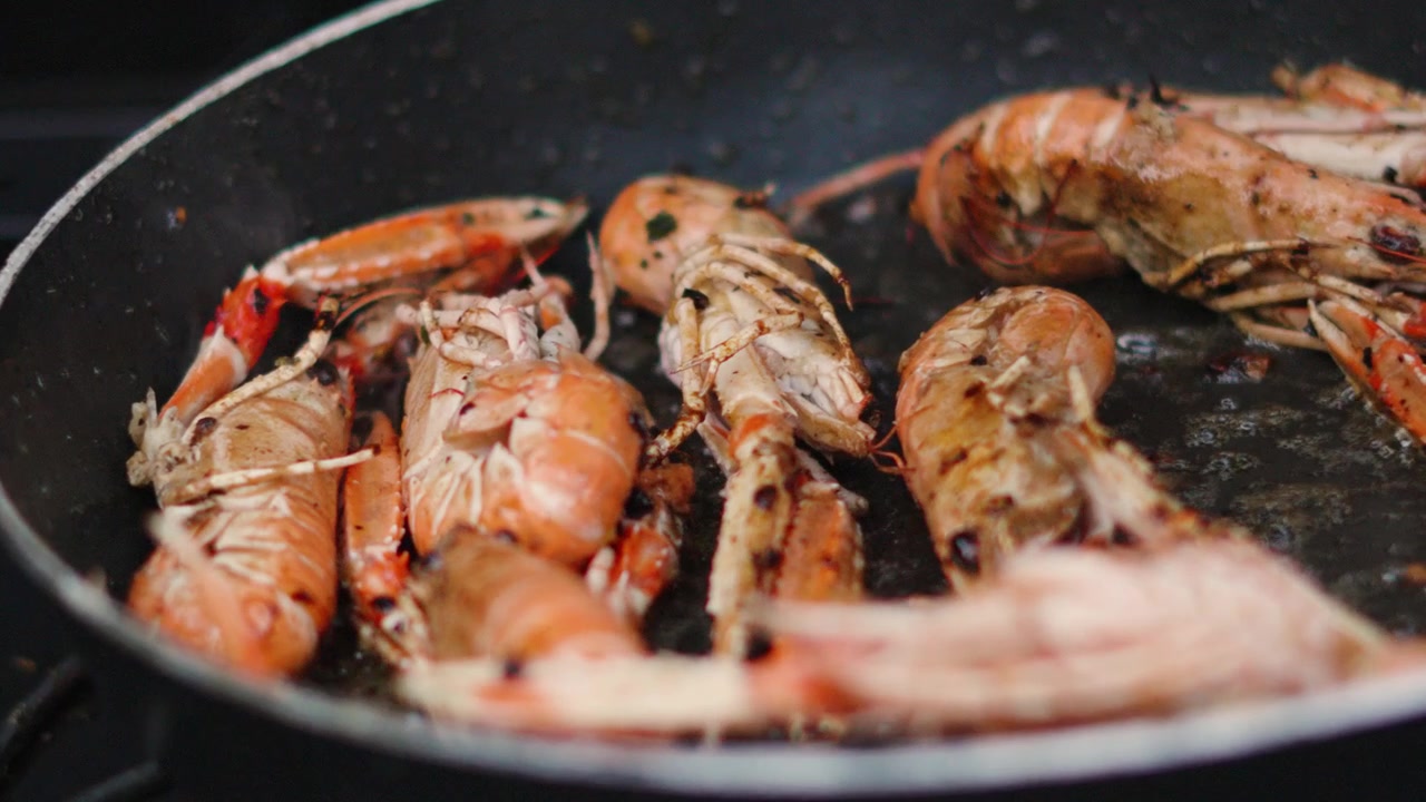 Pushing Shot Towards Fresh Langoustines Being Turned by Hand in Hot Pan. Shellfish Seafood being Cooked Outdoors in Slow Motion. Norway Lobster.