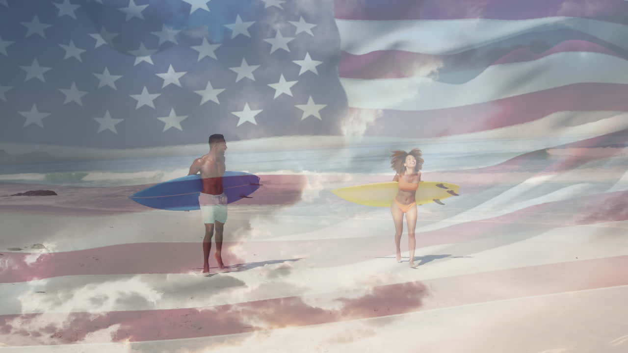 bandera estadounidense ondeando contra una pareja afroamericana con tablas de surf corriendo en la playa