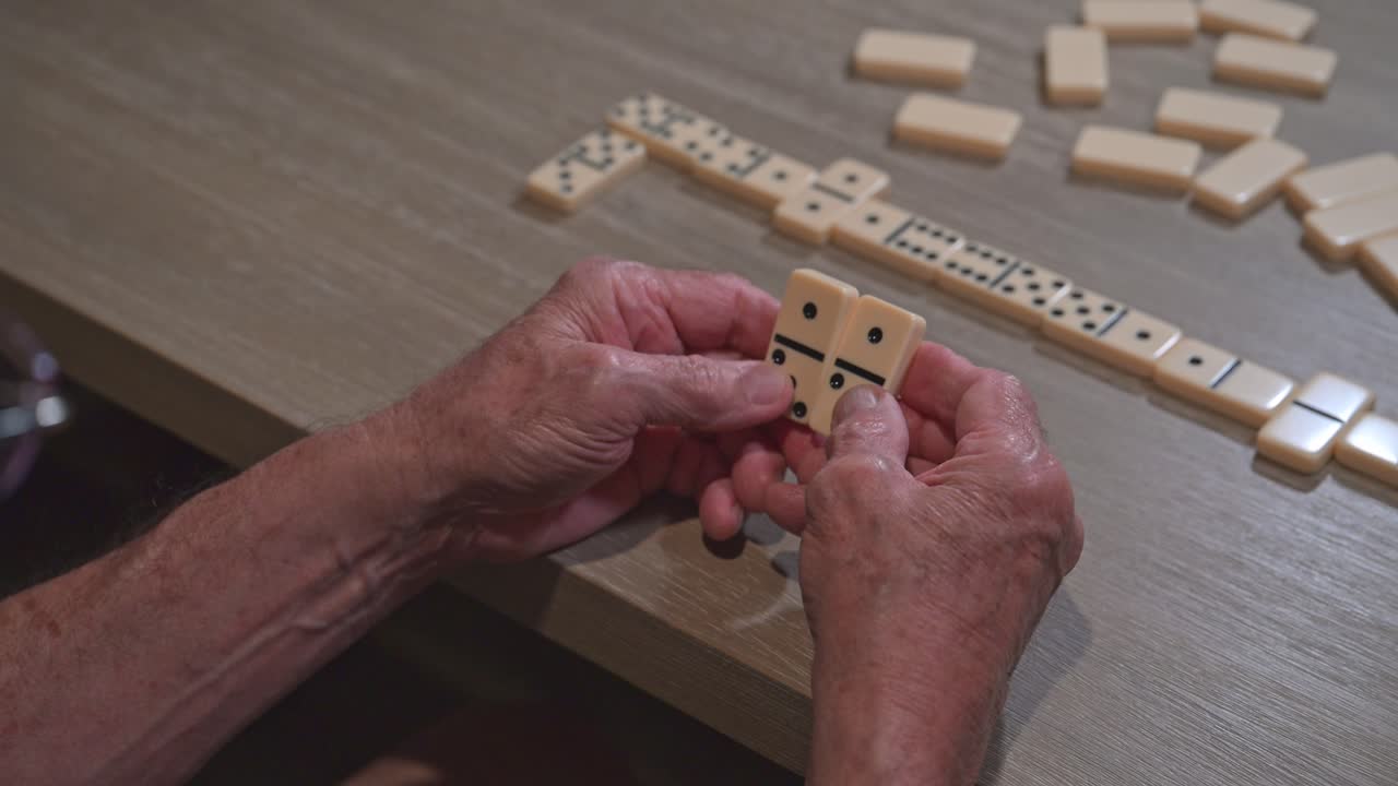senior citizen flips a domino around as he plans his next late night gaming move