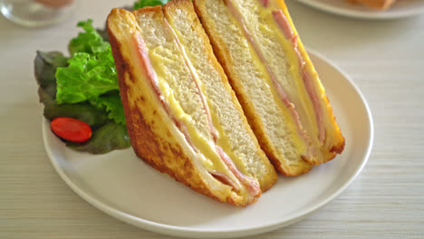 Sándwich de jamón y queso casero en la placa blanca.