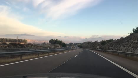 Conducir-Un-Automóvil-En-Una-Carretera-A-Través-De-Las-Montañas-En-Una-Mañana-Soleada