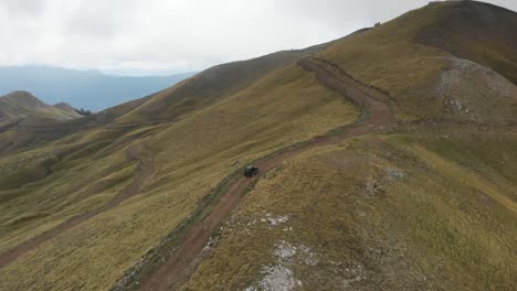 Drone-Video-Seguir-Coche-Montaña-Sinuoso-Camino-De-Tierra-Gramos-Grecia-Verano-Nublado