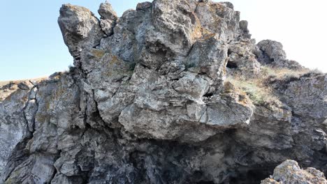 natural rocky cliff with a small cave entrance and lichen-covered boulders