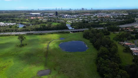 Aerial-over-Mudgeeraba-Creek-moving-towards-M1-and-Surfers-Paradise,-Gold-Coast,-Queensland,-Australia