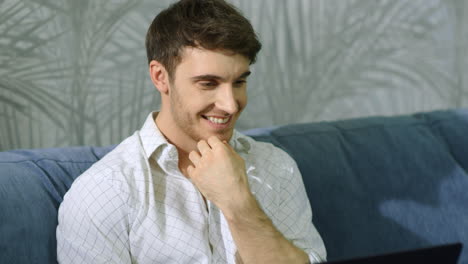 hombre feliz mirando la pantalla de la computadora en el interior. hombre feliz usando una computadora portátil en la habitación de casa