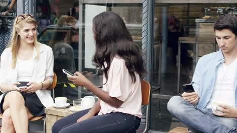 amigas compartiendo juntos usando un teléfono inteligente en un café urbano