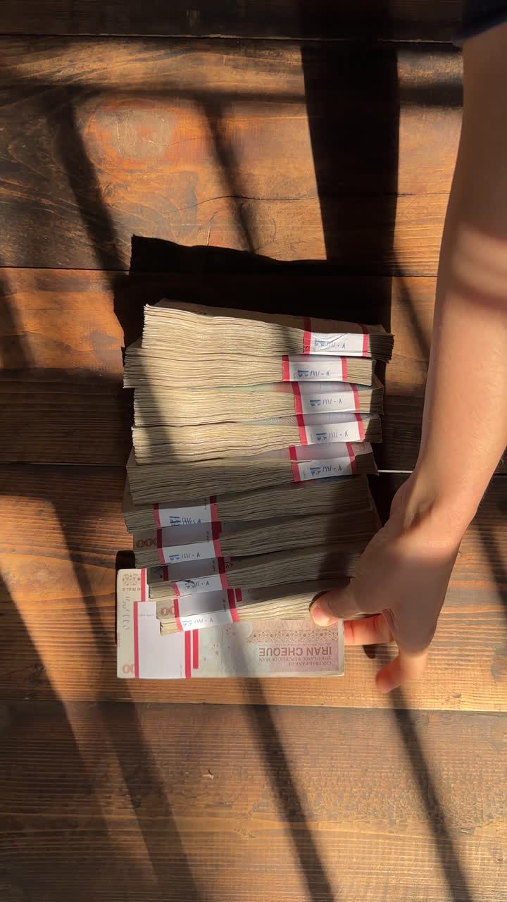 vertical video iranian banknote bundle 100 million rials versus us dollar cash wooden table background economic crisis inflation banking finance business investment payment income bankruptcy sanctions