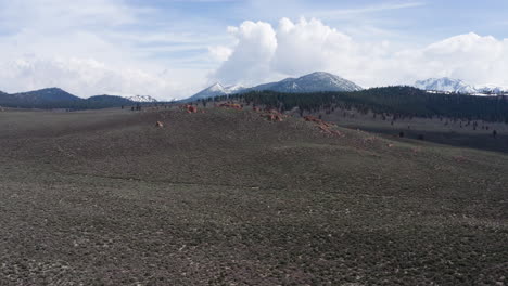 Crater-mountain-and-aeolian-buttes-in-california-with-snowy-peaks-in-the-distance,-aerial-view