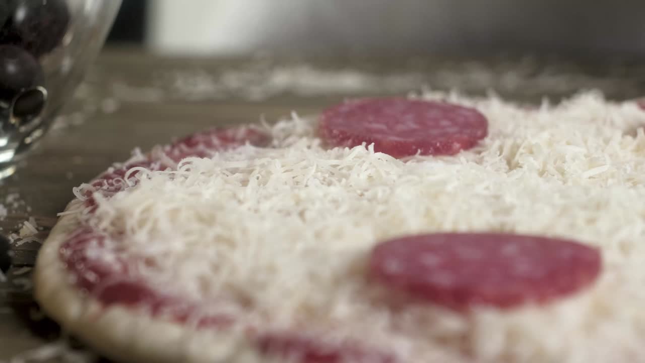 el cocinero pone salchichas picadas en una pizza con queso. preparación de platos italianos. disparo panorámico