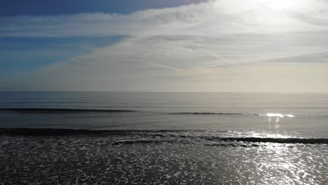 stationary shot of gentle waves rolling onto a beach on a beautiful sunny day