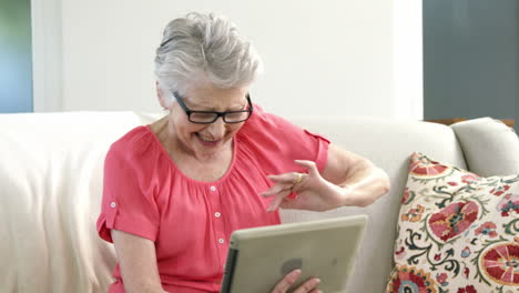 senior woman using digital tablet in living room