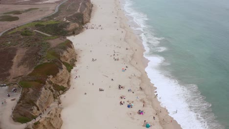 aerial: drone, half moon bay beach cliffs and people enjoying the beach, flying forward view