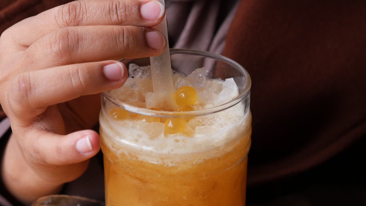 Pipetli bir bardak bubble tea tutan bir kişinin yakın çekimi