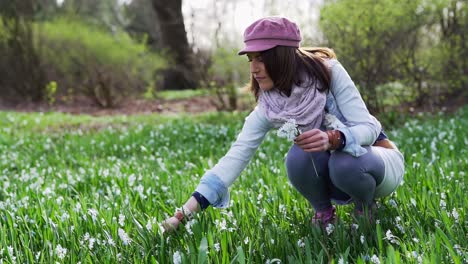 mujer recogiendo flores de lirio blanco de los valles en un parque recogiéndolas en la mano