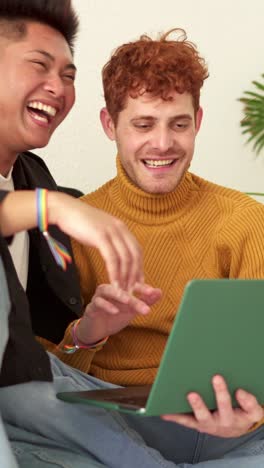 happy lgbtq+ couple laughing while using a laptop