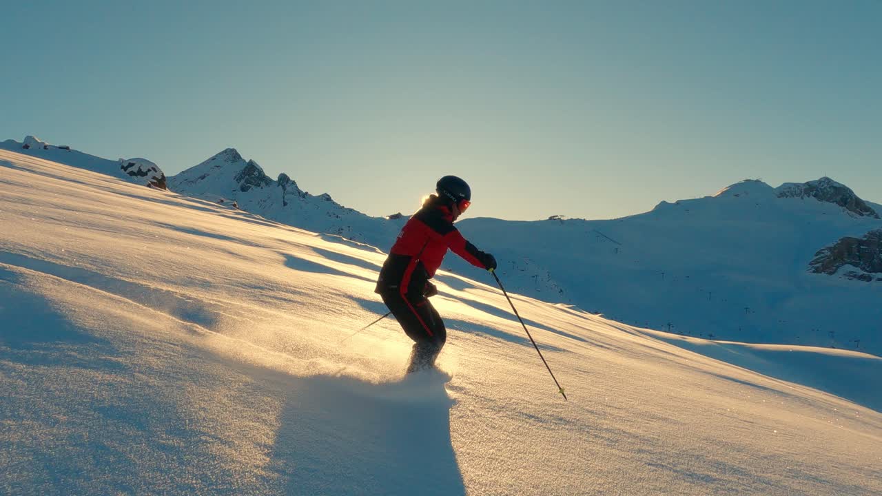 Male ski pro freeride skiing in fresh powder snow with beautiful sunset light in untrackt offpist backcountry. Follow camera skiing in the swiss alps with pro skier.
