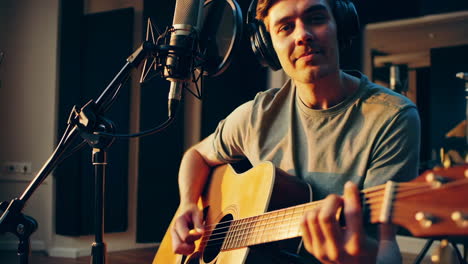 hombre tocando la guitarra acústica en un estudio de grabación