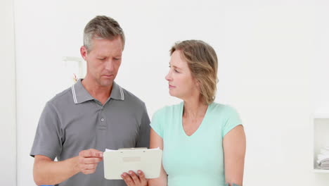 Doctor-showing-clipboard-to-his-patient-with-crutch