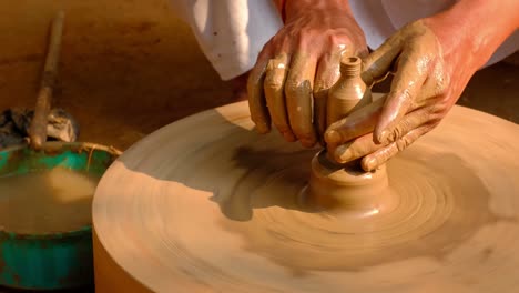 skilled hands of potter shaping the clay on potter wheel and sculpting clay pot jar. shilpagram, udaipur, rajasthan, india