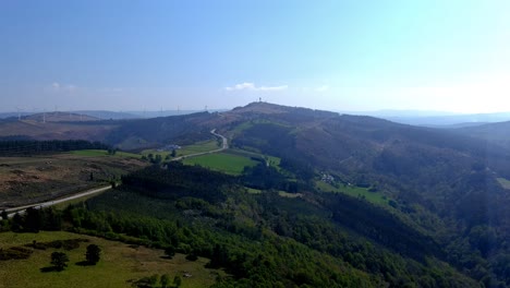 Kleine-ökologische-Bauernhöfe-In-Den-Bergen-Mit-Wäldern-Und-Wiesen,-Die-Durch-Eine-Straße-Verbunden-Sind,-Und-Windkraftanlagen-Im-Hintergrund