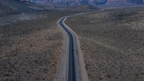 Overhead-shot-following-a-car-to-reveal-the-stunning,-snow-dotted-red-rocks-of-the-Ruby-Mountains-at-sunrise