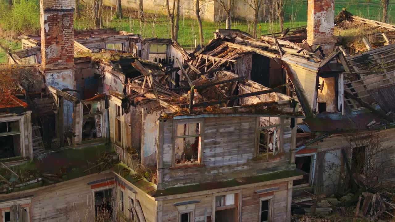 Charred wooden house partially collapsed after fire, morning light on ruins