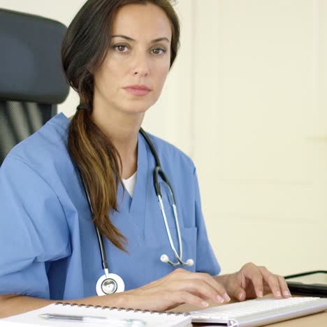 joven doctora sentada escribiendo en su oficina