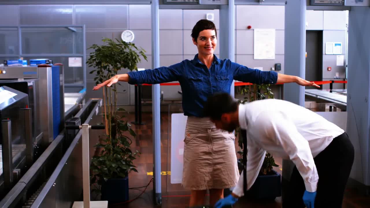 personal de seguridad masculino usando detector de metales en una mujer