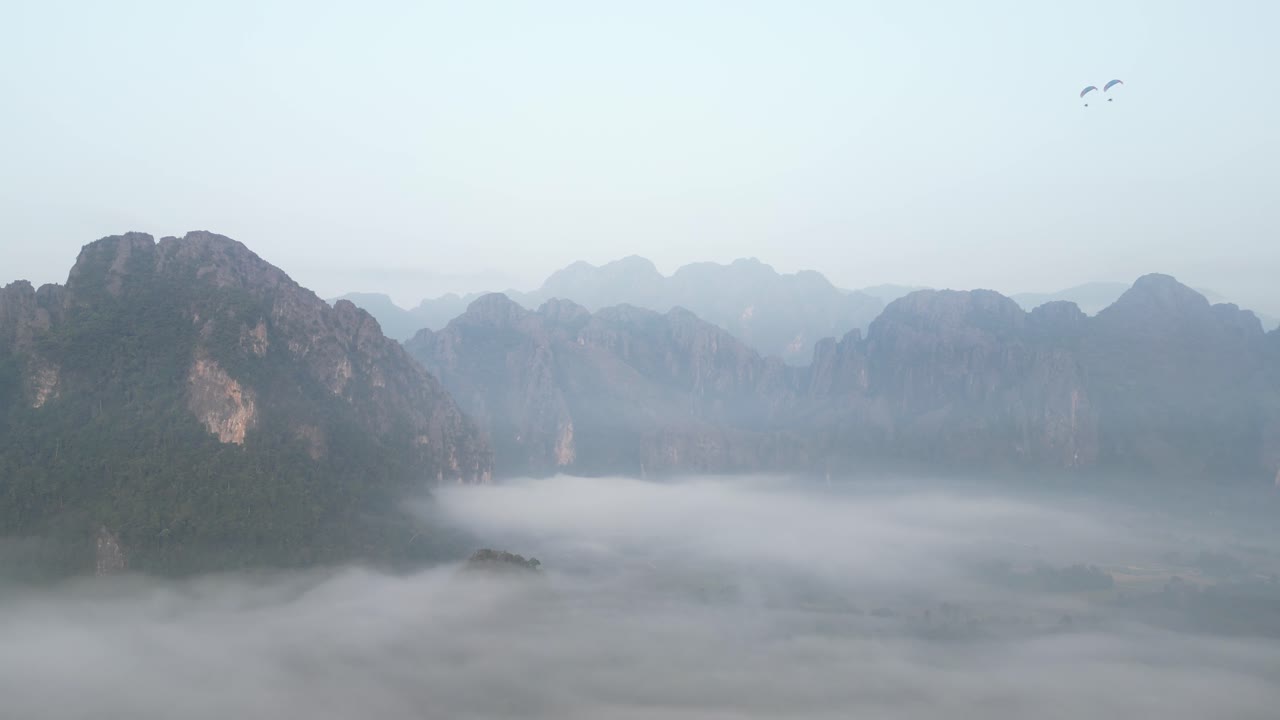 drone shot of morning fog shrouding cliffs in Vang Vieng, the adventure capital of Laos