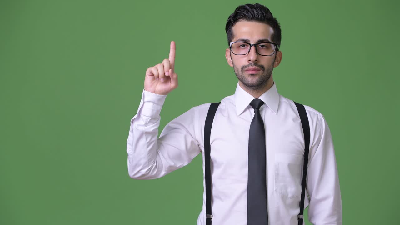 joven empresario persa barbudo y guapo contra un fondo verde