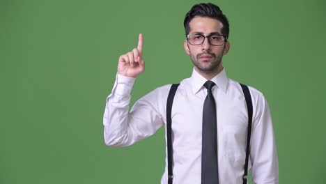 joven empresario persa barbudo y guapo contra un fondo verde