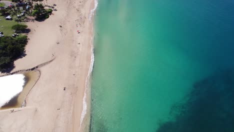 aerial-footage-along-the-North-shore-of-the-island-of-Oahu-Hawaii-showing-white-sand-beaches-separtaing-the-clear-turquoise-water-of-the-Pacific-ocean-from-the-lush-rainforest-covered-mountains