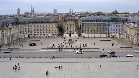 Place-De-La-Bourse-En-Burdeos-Francia-Con-Gente-En-Su-Plaza-Caminando,-Tiro-De-Pedestal-De-Ascensor-Aéreo