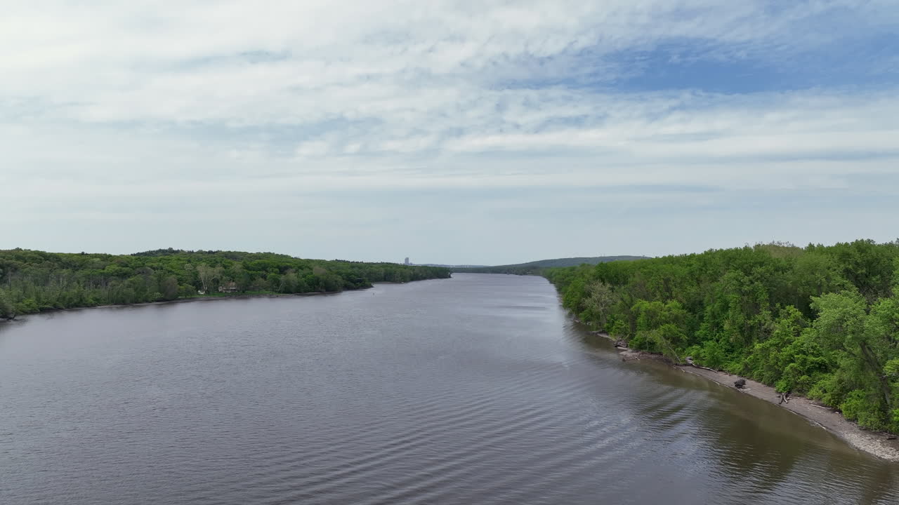 100 foot level drone video showing the Hudson River shoreline headed north with the skyline of Albany NY in the far distance.