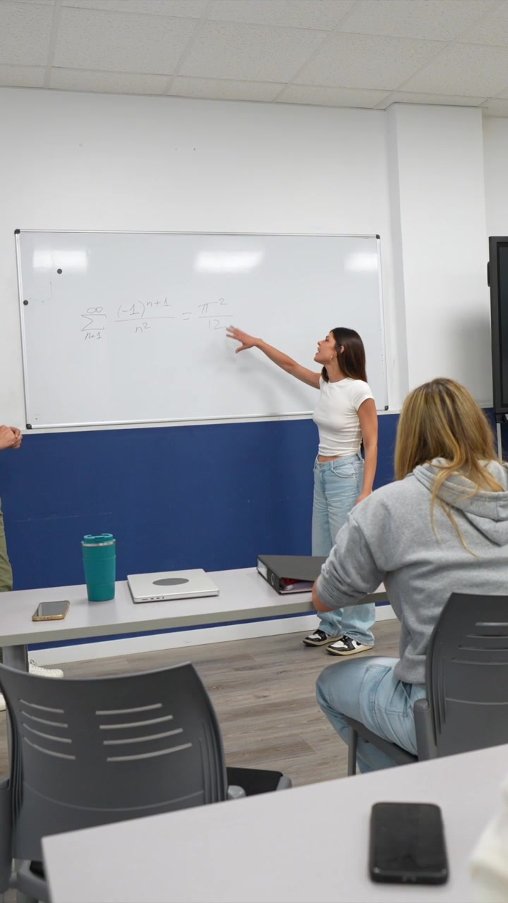 Insegnante e studente che discutono un'equazione matematica sulla lavagna in classe