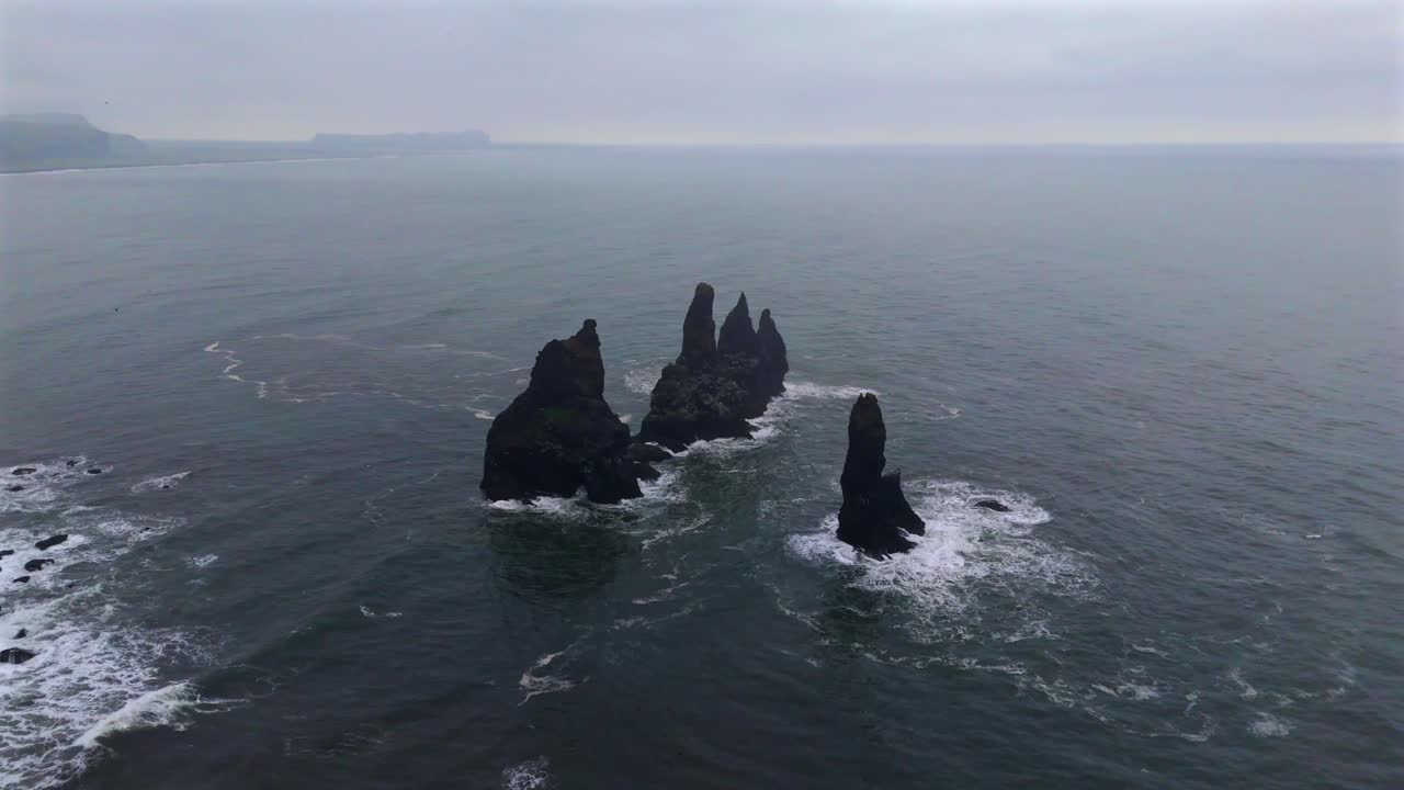 Immerse yourself in the breathtaking scenery of Reynisfjara, where the black sand beach meets dramatic cliffs, captured beautifully from the sky.