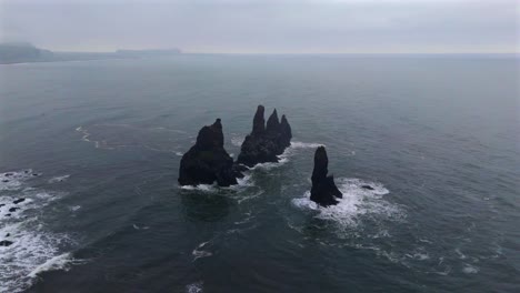 immerse yourself in the breathtaking scenery of reynisfjara, where the black sand beach meets dramatic cliffs, captured beautifully from the sky.