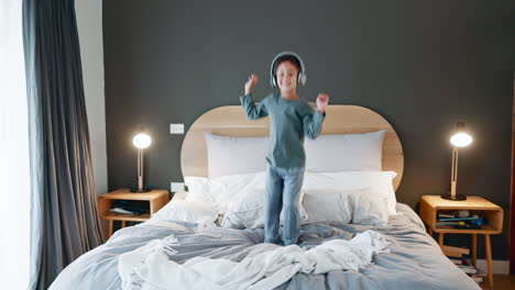 niño joven, bailando y saltando a la cama en casa con música