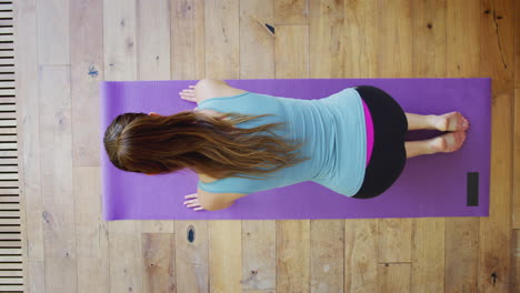 overhead view of young woman doing yoga on wooden floor