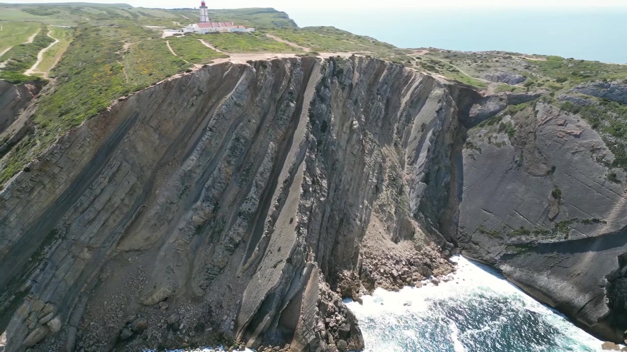 Aerial drone footage of Cabo Espichel, Portugal: dramatic Atlantic cliffs, rugged coastline and vast ocean landscape under natural light. Ideal for travel and nature projects.