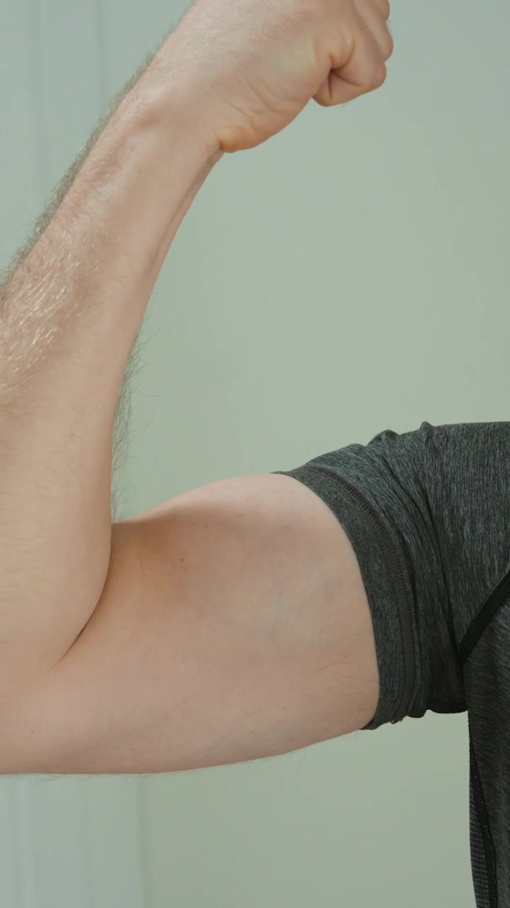 Primo piano di un uomo che tocca e controlla il suo muscolo bicipite, mostrando fitness, forza, bodybuilding, progressi nell'allenamento, salute del braccio, crescita muscolare, motivazione all'allenamento e condizione fisica.