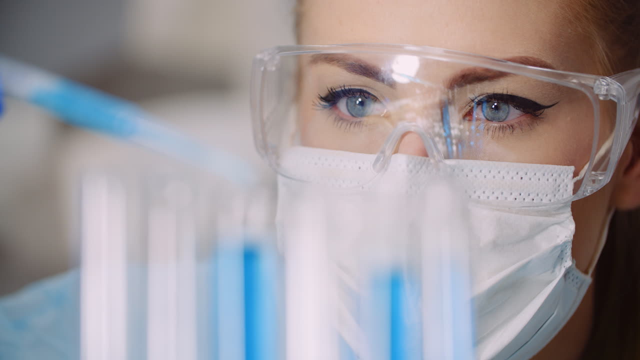 врач осторожно капает лекарство из пипетки в стеклянные пробирки для анализа днк в лаборатории 5