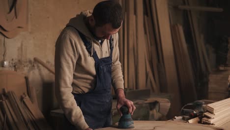 il falegname nella sua piccola officina sta lavorando alla lucidatura del pezzo di legno