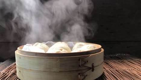 side view of uncovering lid of cooked steamed buns showing steam rising