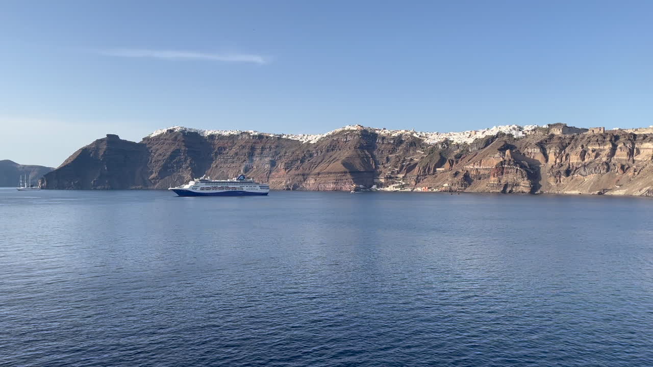 Celestyal Journey anchored offshore near the dramatic cliffs of Santorini, showcasing a scenic Mediterranean cruise experience. Perfect for South Aegean cruising content.